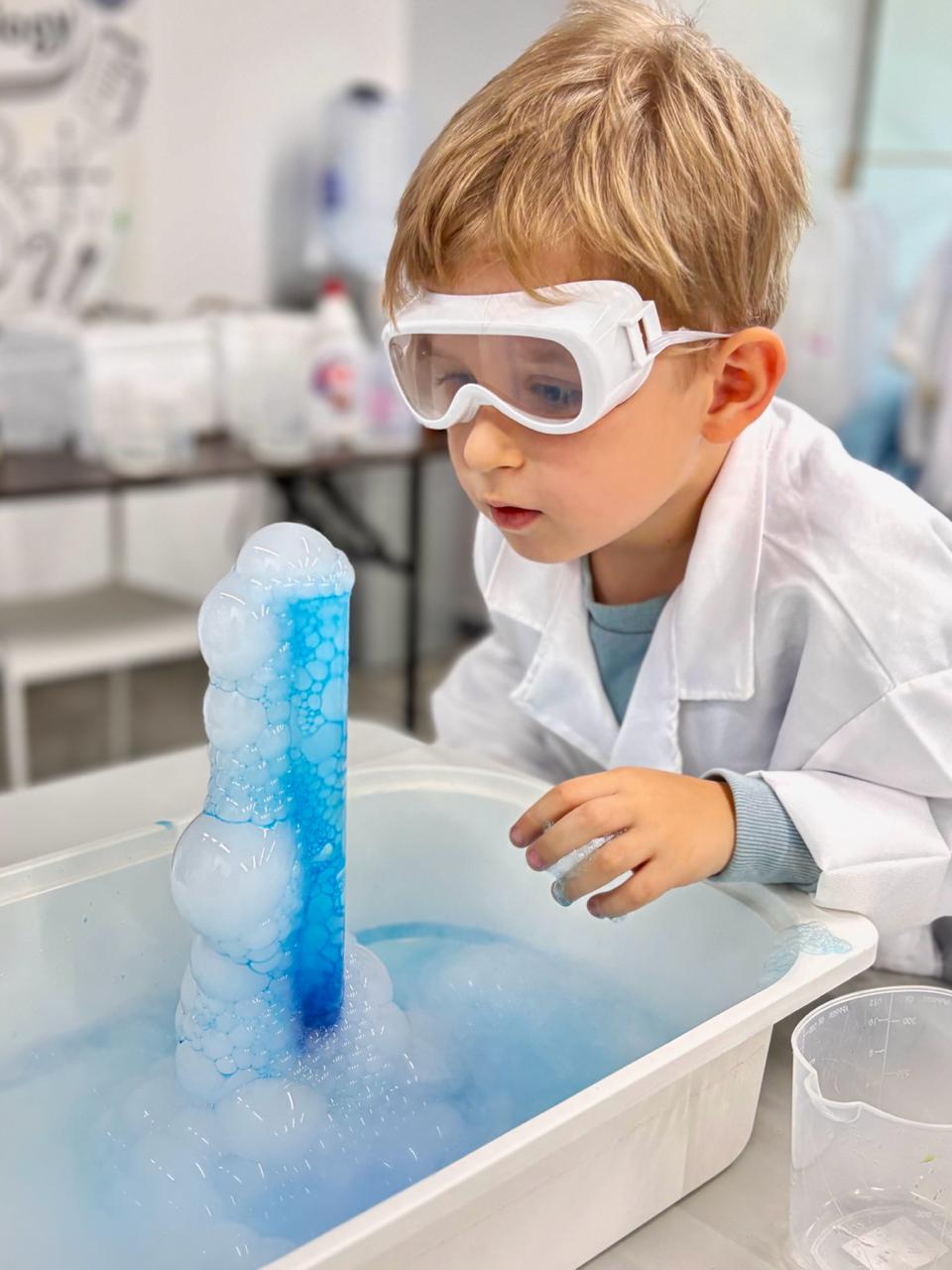 A young scientist observing a blue bubble experiment